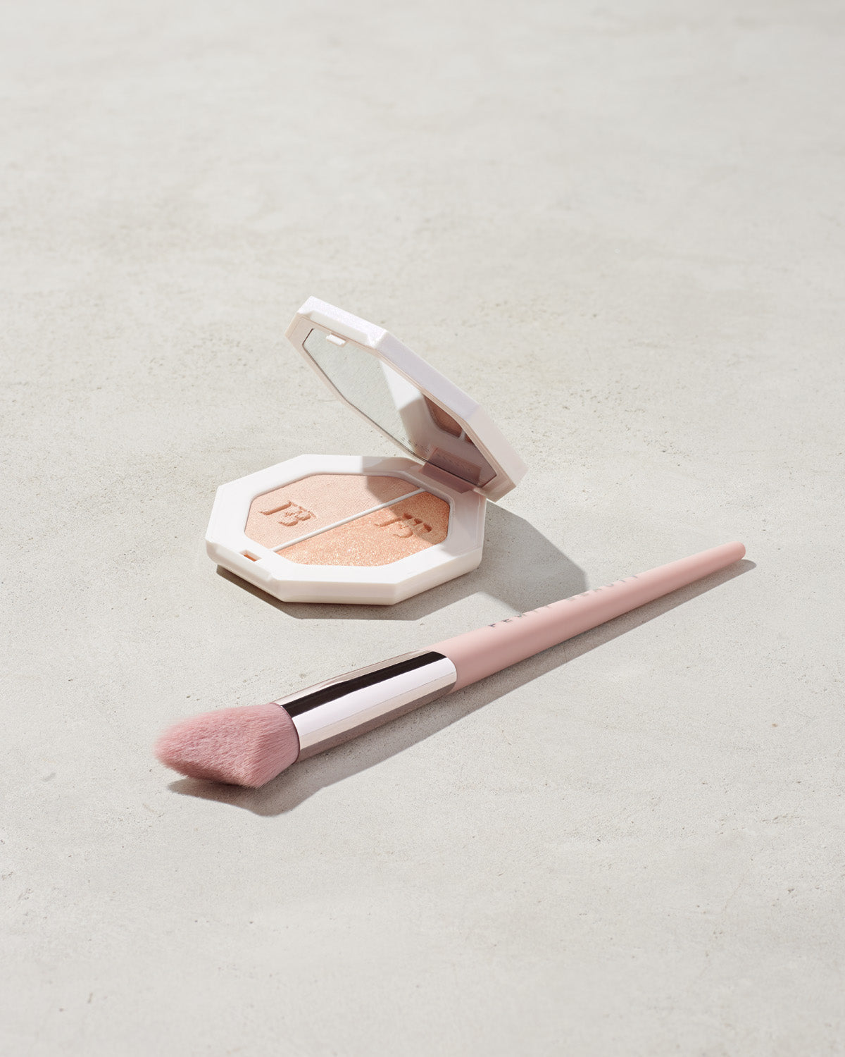 imagery of killawatt freestyle highlighter in shade lightning dust/fire crystal on a concrete background with the cheek hugging highlight brush