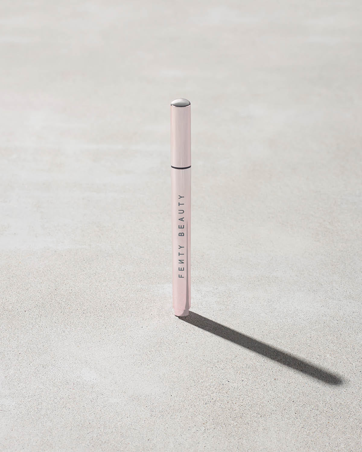 Closed Flyliner Longwear Liquid Eyeliner standing on a light grey concrete surface. The exterior showcases a chic light metallic pink finish.