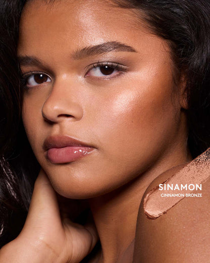 Medium-deep skin toned model wearing match stix shimmer in shade sinnamon.