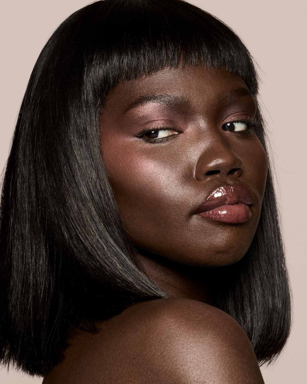 deep skin toned model wearing gloss bomb universal lip luminizer in shade Hot Chocolit