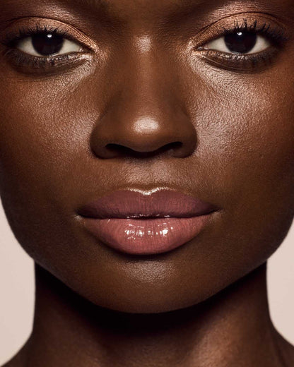 deep skin toned model wearing gloss bomb cream in shade fenty glow