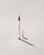 Fenty Beauty Flyliner Longwear Liquid Eyeliner in shade In Big Truffle with cap off on concrete background