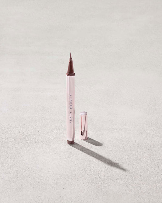 Fenty Beauty Flyliner Longwear Liquid Eyeliner in shade In Big Truffle with cap off on concrete background