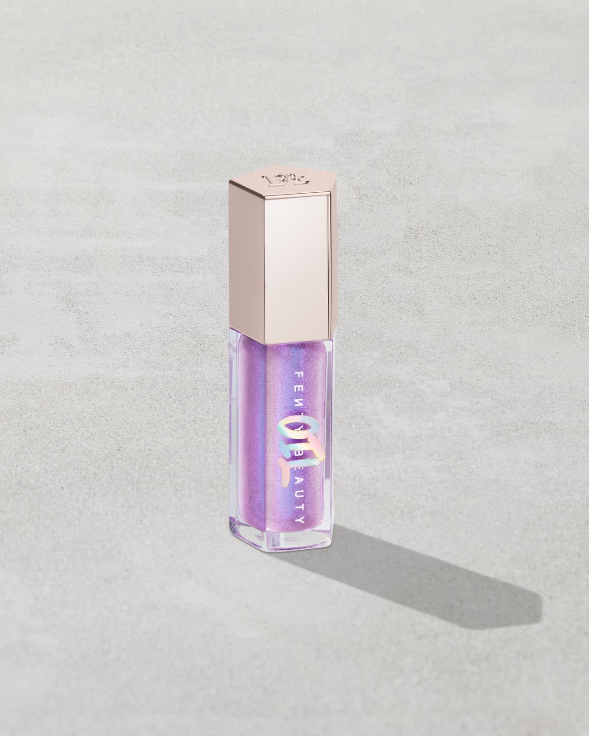 Gloss Bomb Oil Luminizing Oil and Gloss in shade Miss Jellyfish product against a concrete background.
