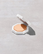 Open product shot of Demi'glow Light-Diffusing Highlighter in shade Pretty Purlz on a concrete backdrop.