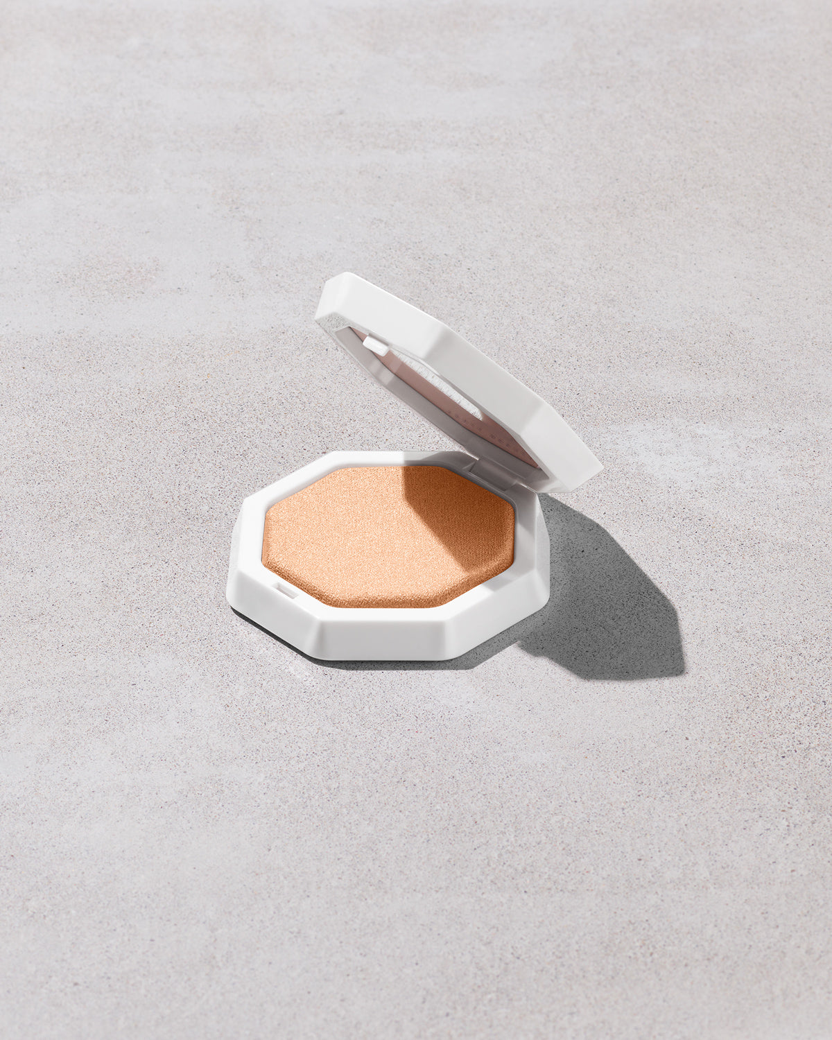 Open product shot of Demi'glow Light-Diffusing Highlighter in shade Pretty Purlz on a concrete backdrop.