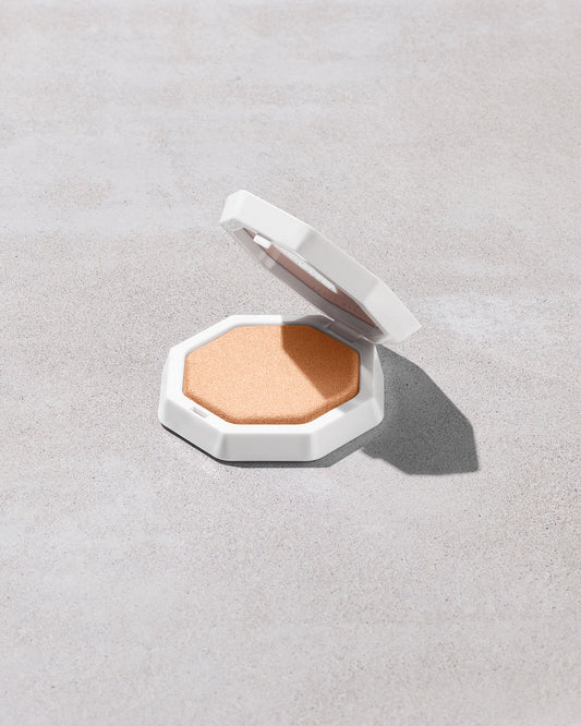 Open product shot of Demi'glow Light-Diffusing Highlighter in shade Pretty Purlz on a concrete backdrop.