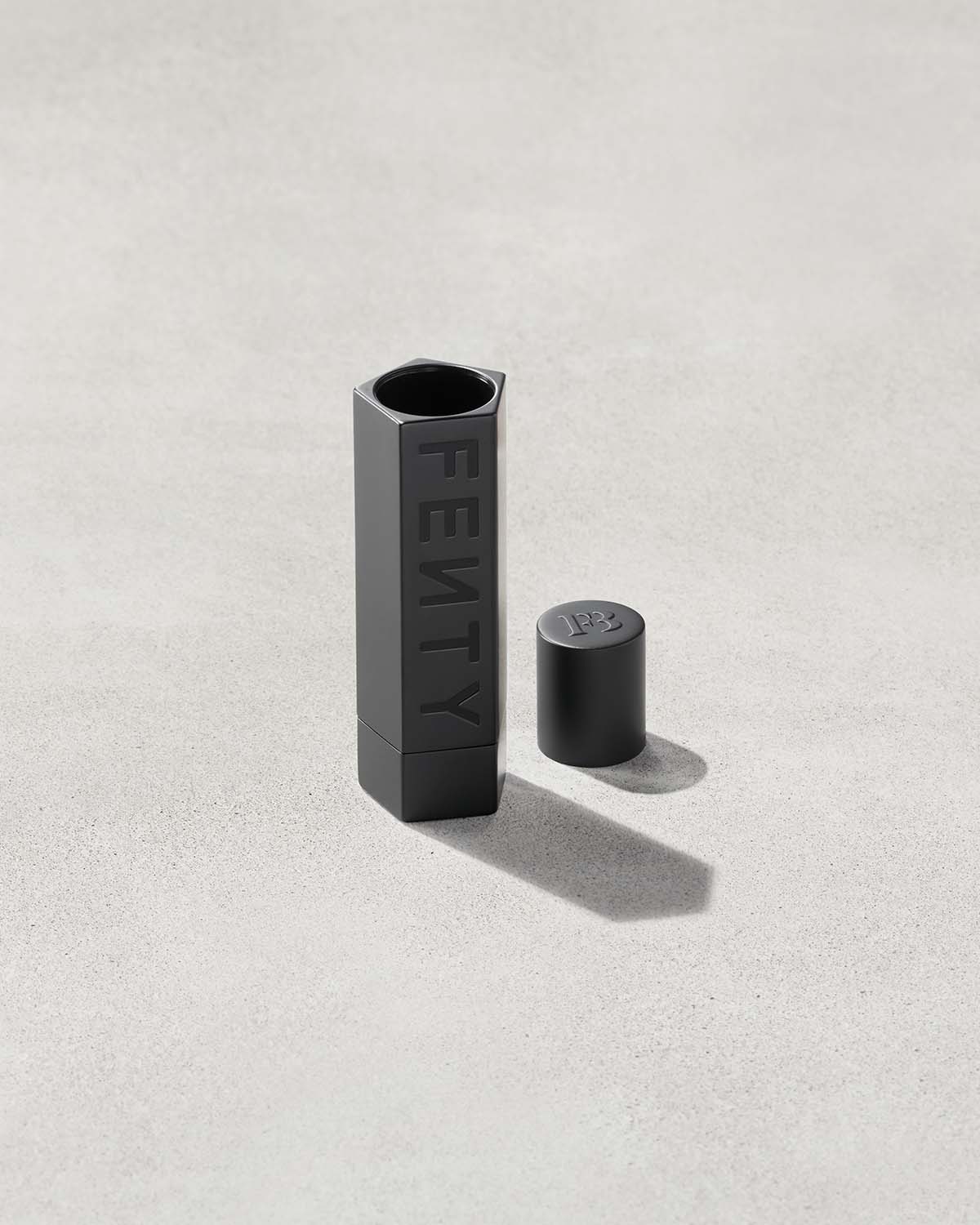 An open Fenty Icon refillable lipstack case in matte black.